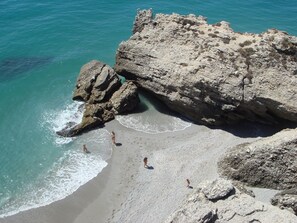 Una playa rocosa con agua turquesa cristalina y una gran formación rocosa.
