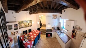 Une cuisine compacte avec un coin repas, dotée d’un sol carrelé, d’une table recouverte d’une nappe rouge et blanche, et d’un four encastré.
