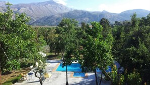 A pool area with a mountain view, surrounded by trees and a clear sky. - Zeus House Gaia (Lasithi Plateau)