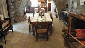 A dining area with a stone archway, wooden furniture, and a view into a kitchen. - Zeus House Gaia (Lasithi Plateau)