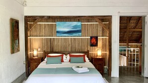 Une chambre à coucher avec une tête de lit en bois, un grand lit avec une literie blanche et turquoise, deux lampes de chevet et un tableau au-dessus du lit.