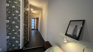 A hallway with a floral wallpaper, a framed picture on the wall, and a bench. - VRIJ van 29 augustus tot 5 september .2 pers studio 5 min lopen  het strand (Westkapelle)