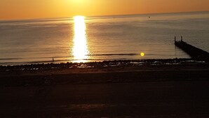 A sunset over a calm sea with a pier extending into the water. - VRIJ van 29 augustus tot 5 september .2 pers studio 5 min lopen  het strand (Westkapelle)