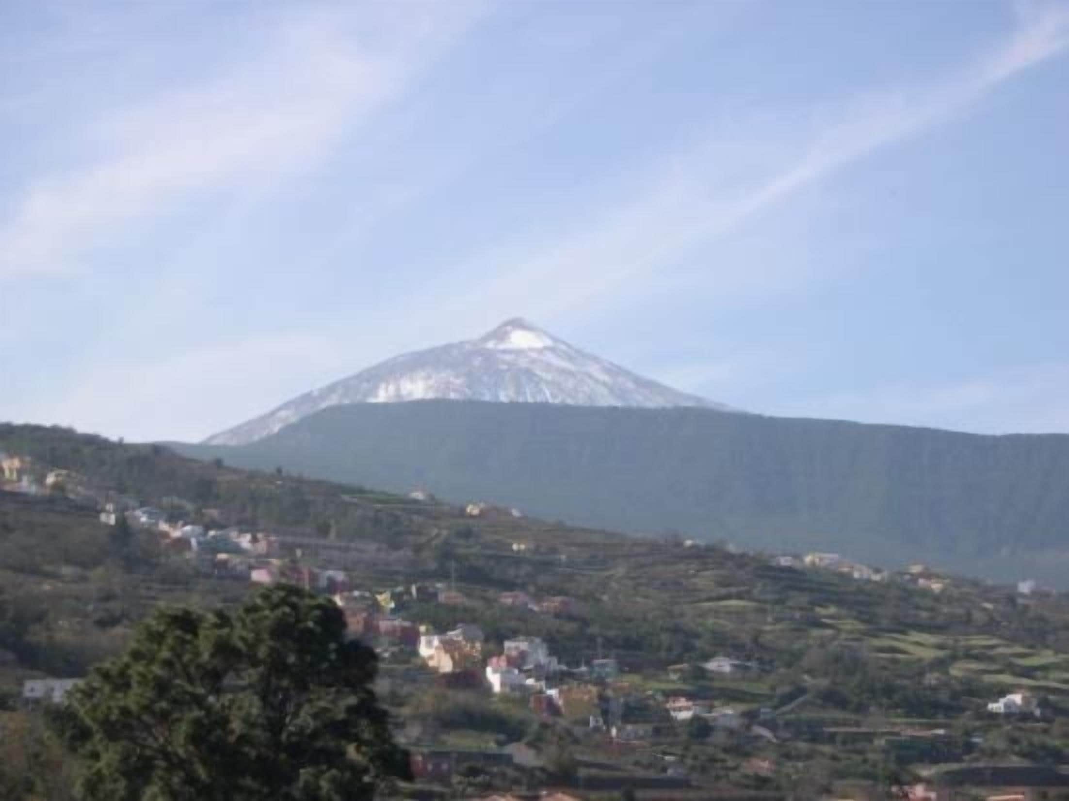 A mountain with a snow-capped peak and a valley with scattered houses.