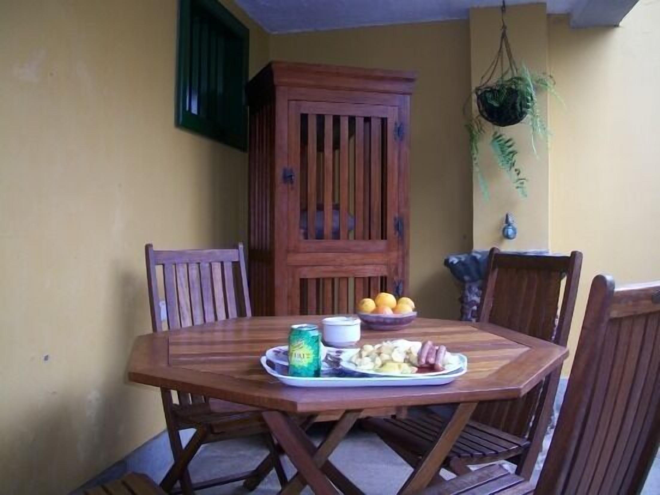 Una mesa de madera con sillas, un aparador y una planta colgante.