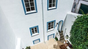 Ein weißes Gebäude mit blauen Fensterrahmen und einer kleinen Außenbereich-Sitzgelegenheit mit Holzmöbeln.