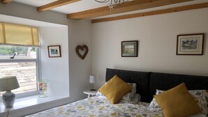 Une chambre à coucher comprenant un lit, deux tables de chevet, une fenêtre avec vue et des éléments de décoration murale.