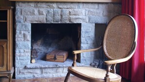 A cozy room with a stone fireplace, a rocking chair, and a framed picture above the fireplace.