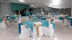 A banquet hall with round tables, chairs, and draped fabric on the ceiling. - Mi Tierra (Cabo Rojo)