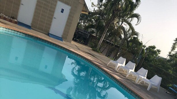 A swimming pool with clear blue water, a tiled deck, and white lounge chairs. - Mi Tierra (Cabo Rojo)