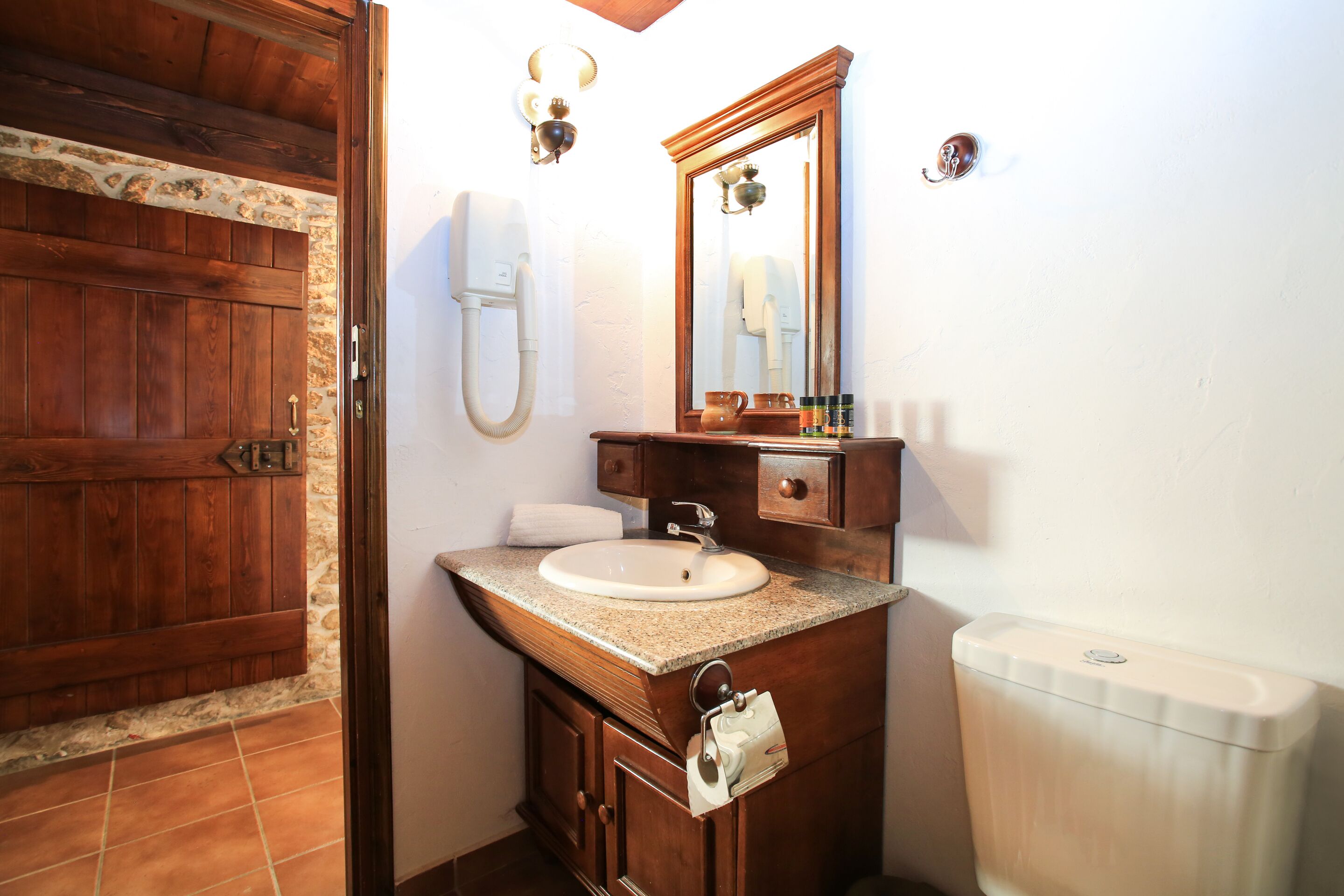 Un bagno con una porta in legno, un lavandino con uno specchio sopra e un water.