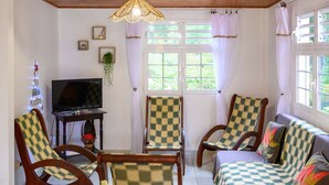 Una sala de estar acogedora con muebles de madera, un televisor y una mesa con flores.