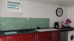 Una cocina con armarios rojos, una encimera blanca, una estufa integrada, un lavabo y un lavavajillas.