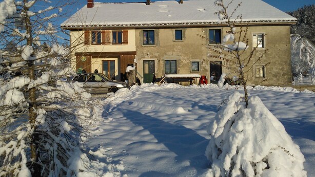 Um edifício de dois andares com telhado coberto de neve e acesso pavimentado.