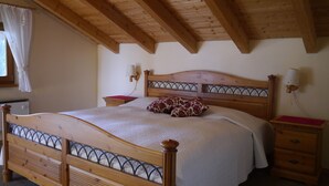 Una cama de madera con cabecera, dos mesitas de noche y una ventana con cortinas.