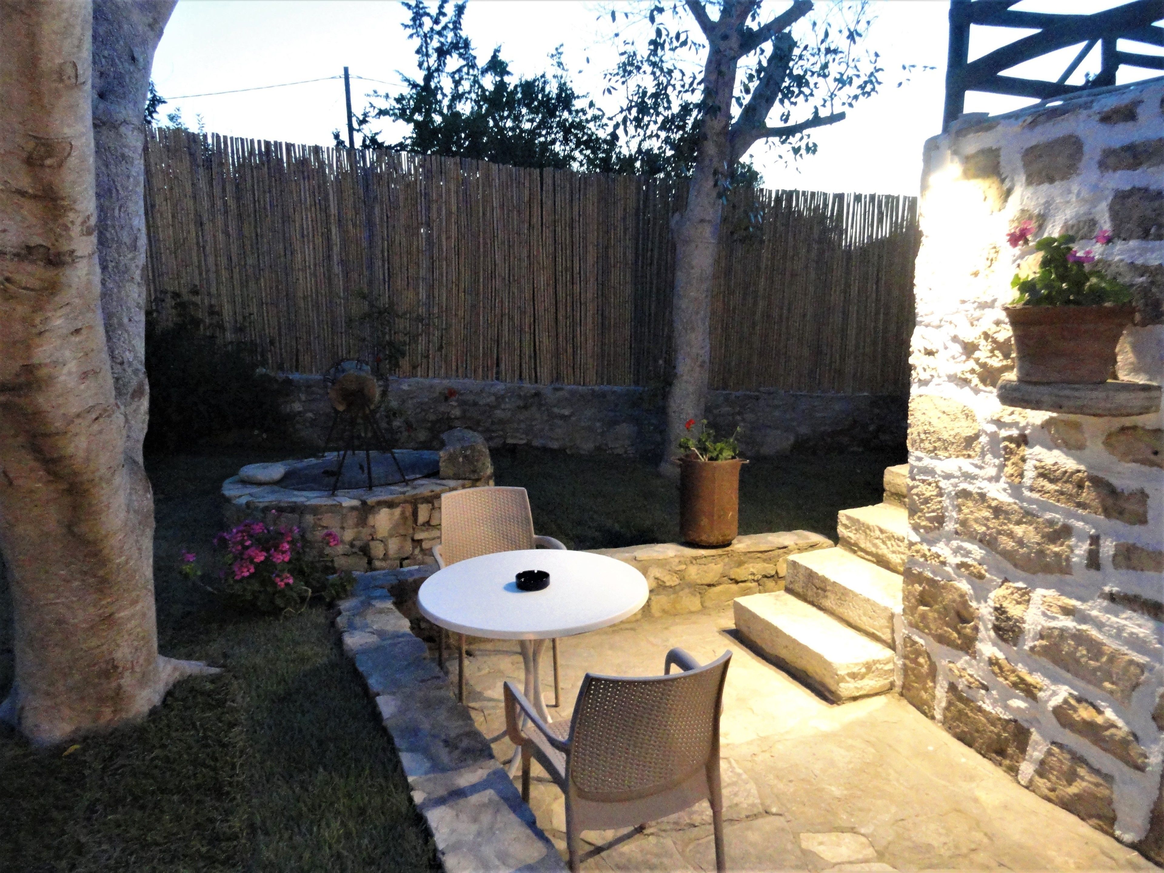 A patio area with a round table and chairs, a stone wall, and a wooden fence.
