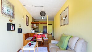 En stue med sofa, spisebord og et køkken i baggrunden.