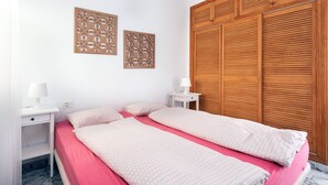 Een slaapkamer met een bed, twee nachtkastjes, een houten kledingkast en decoratieve wandpanelen.