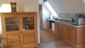 A kitchen with wooden cabinets, a microwave, and a clock on top.