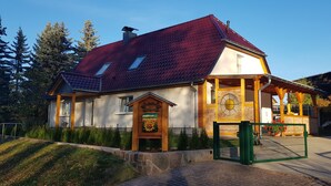 A traditional wooden house with a red-tiled roof, a wooden porch, and a brick entrance.