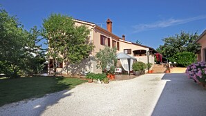 A two-story building with a gravel driveway, potted plants, and a clear blue sky.
