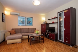 Una sala de estar con un sofá, una mesa de centro, un televisor y un aparador.