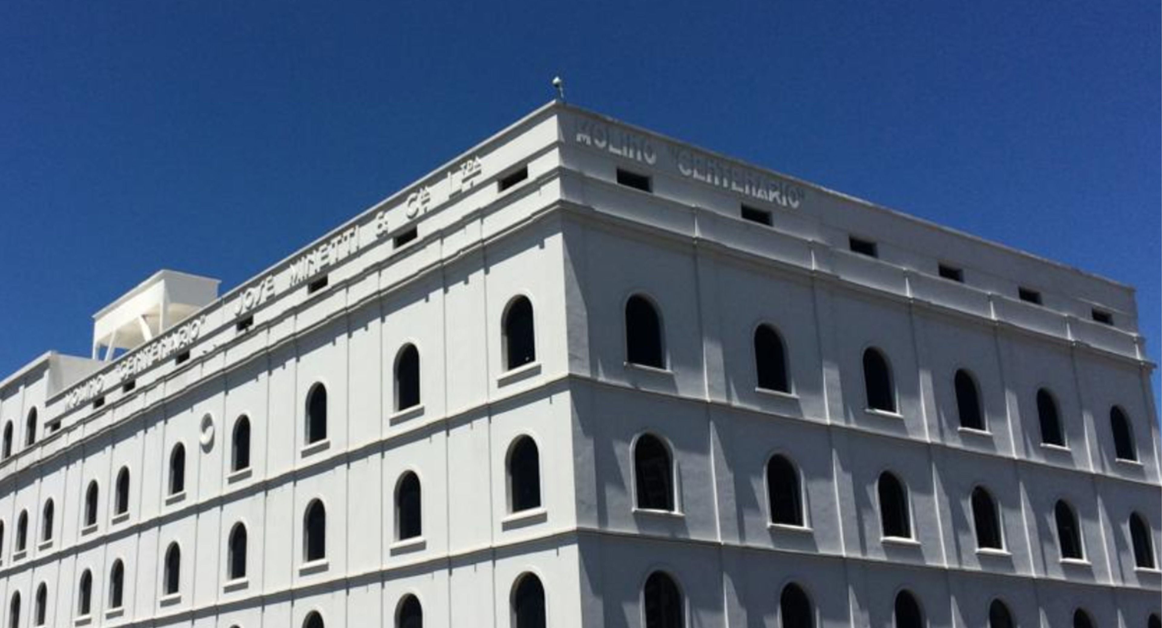A multi-story building with a white facade and numerous arched windows.