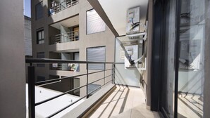 Een modern gebouw met een glazen balkon, metalen leuning en een betegelde vloer.