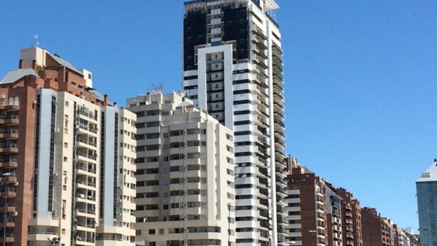 Een hoog gebouw met meerdere verdiepingen, met een combinatie van woon- en commerciële ruimtes.