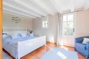 Une chambre à coucher avec un lit, une table de chevet, une commode, une fenêtre et une porte.