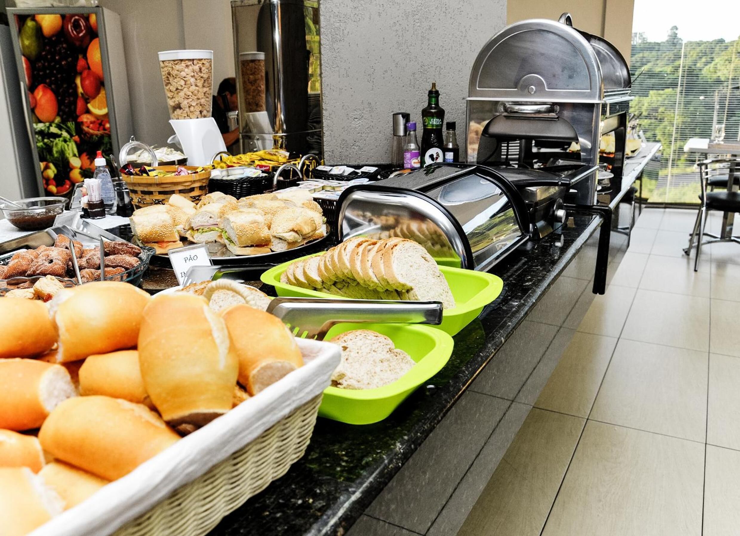 Un bufé con diversas opciones de comida, incluyendo pan, sándwiches y pastelería.