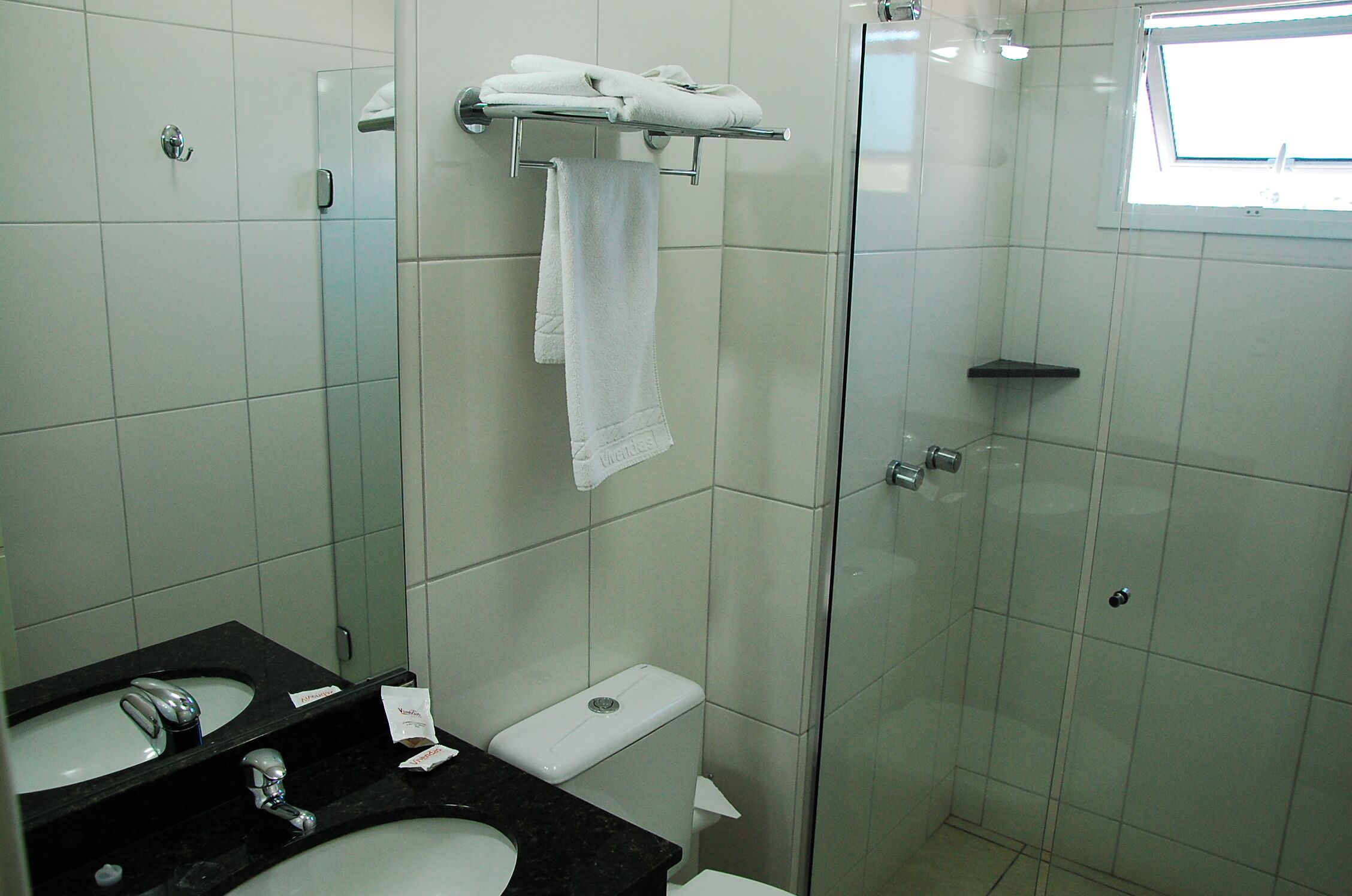 Ein Badezimmer mit einer Duschkabine, einem schwarzen Waschbecken und einer weißen Toilette.