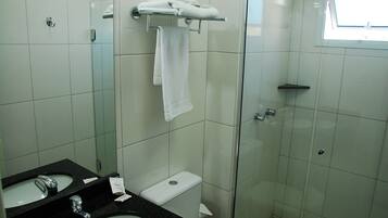 Ein Badezimmer mit einer Duschkabine, einem schwarzen Waschbecken und einer weißen Toilette.