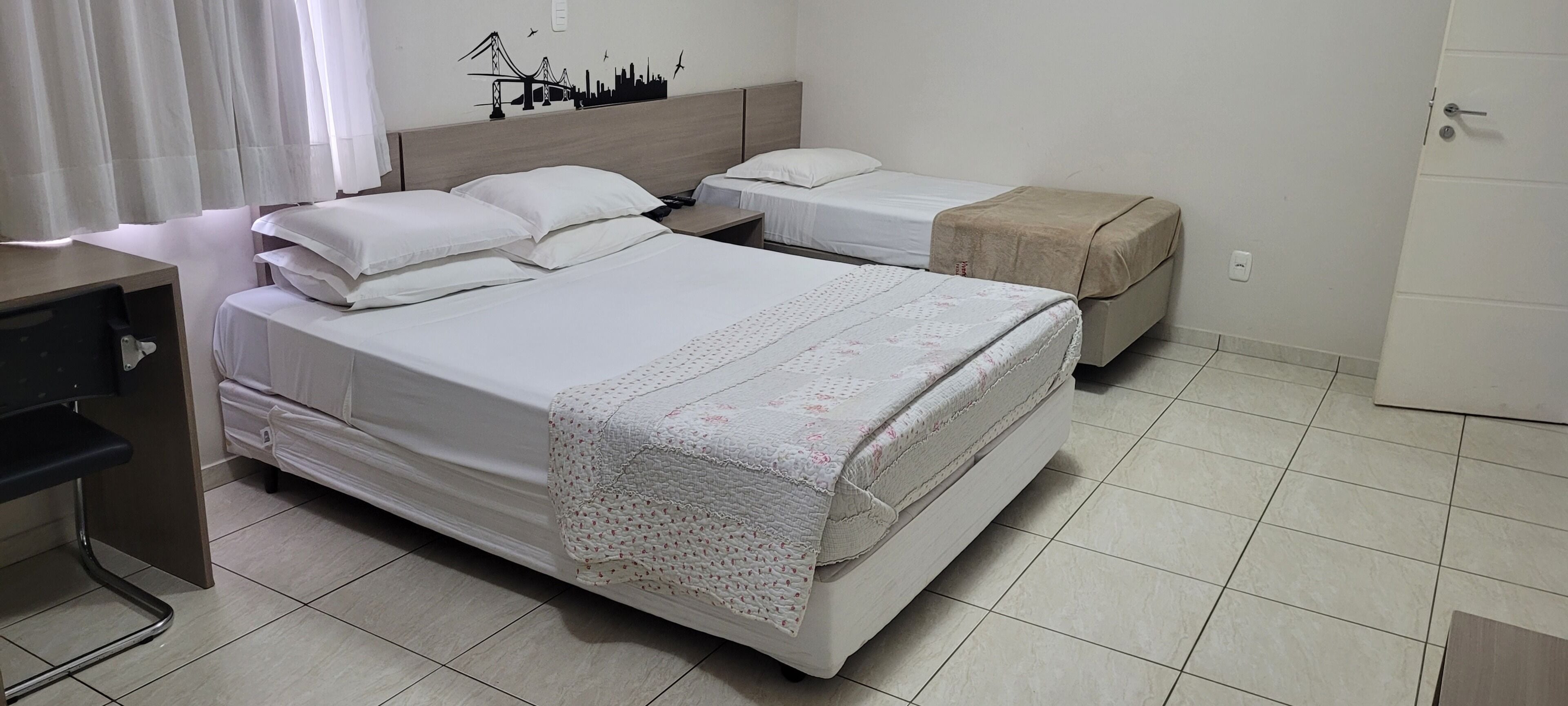 Una habitación de hotel con dos camas, un escritorio y una puerta.