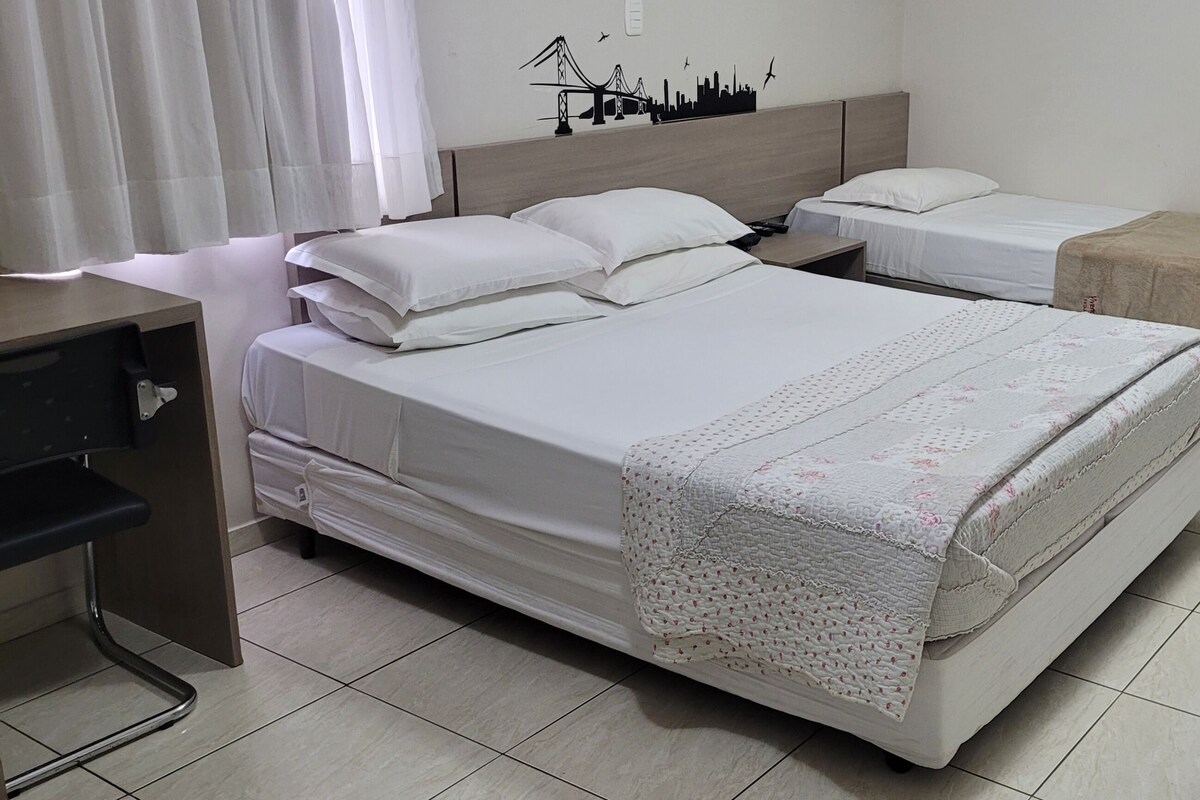 Habitació d'hotel amb dos llits, una taula i una porta.