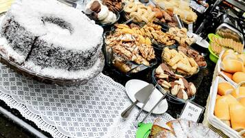 Un bufé con diversos alimentos, incluyendo un pastel cubierto de azúcar glas, fuentes de carnes, quesos, pastelería y pan.
