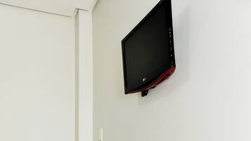 Un mostrador de recepción con un jarrón de flores, un televisor de pantalla plana y una silla.