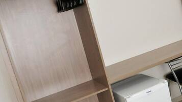 A wardrobe with a mirror, a flat-screen TV mounted on the wall, and a small white appliance on the floor.