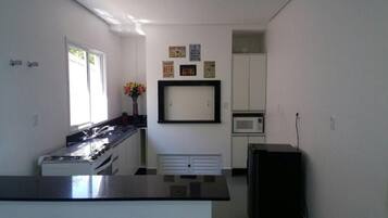 A kitchen with a stove, microwave, and cabinets. There are framed pictures on the wall.