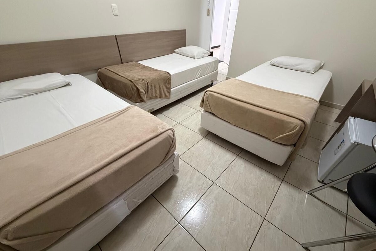 Habitació d'hotel amb tres llits, un escriptori i una cadira.