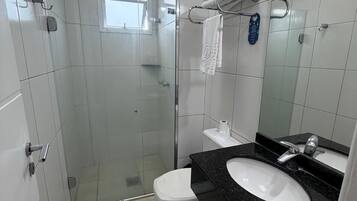 A bathroom with a glass shower enclosure, a white toilet, a black countertop sink, and a mirror.