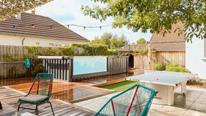 Un patio exterior con mesa de ping pong, dos sillas y una pequeña piscina.