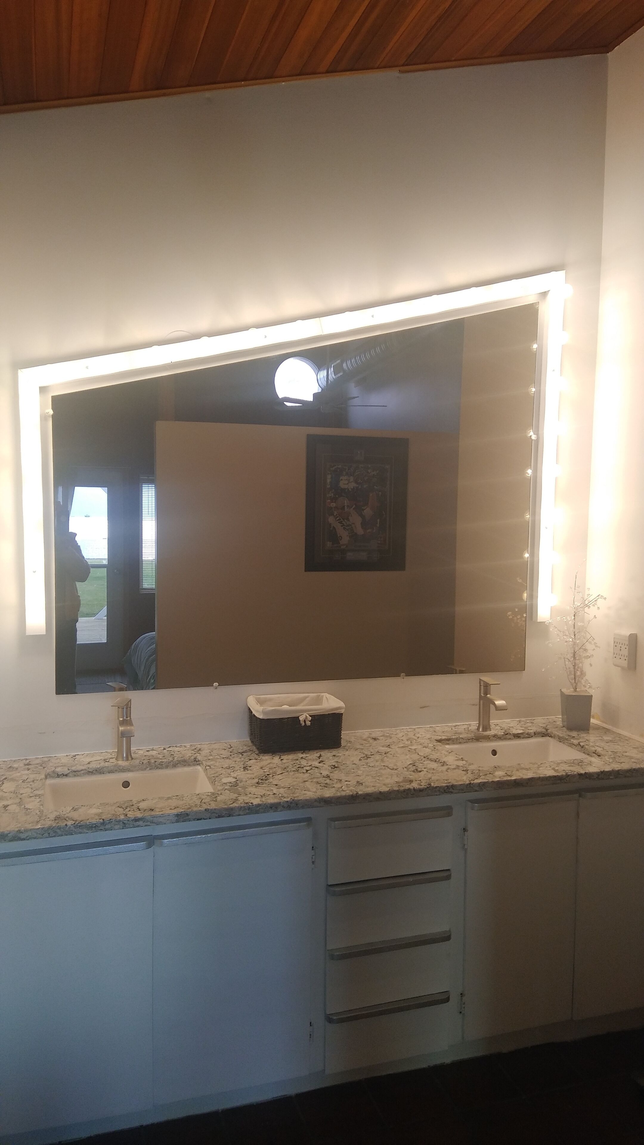 Une salle de bain avec un grand miroir, un meuble-lavabo et un évier.