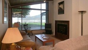 A living room with a sofa, a coffee table, a TV, and a fireplace. - Vernon Sandy Beachfront Home ! (Vernon)