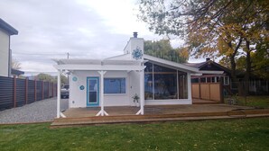A small, single-story house with a white exterior, a blue door, and a large window. - Vernon Sandy Beachfront Home ! (Vernon)
