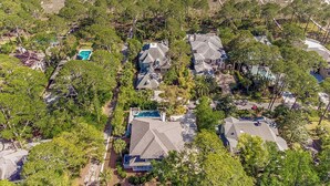 Vista aérea de una zona residencial con casas, árboles y una playa al fondo.
