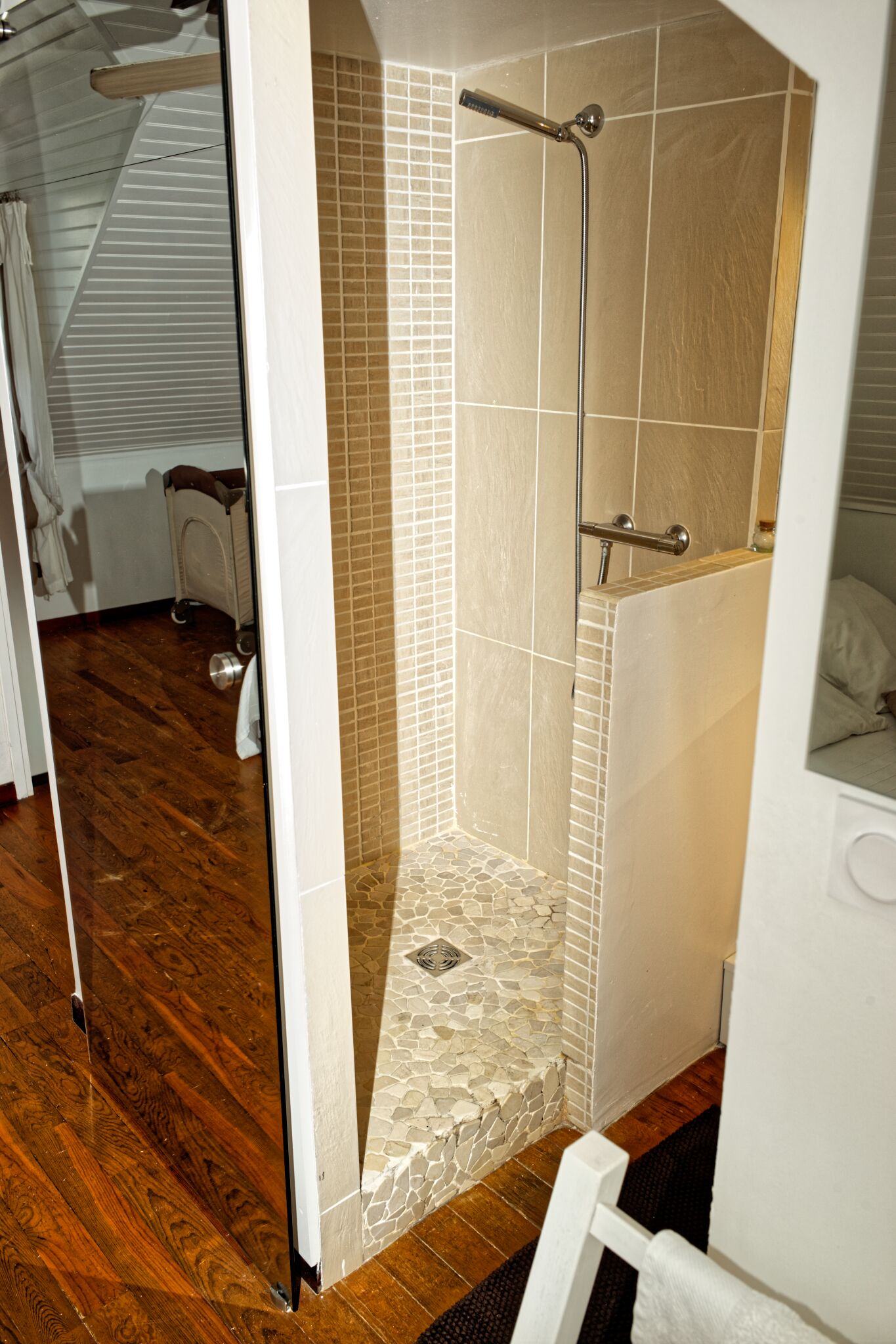 Un espacio de ducha con paredes de azulejos y suelo de madera.