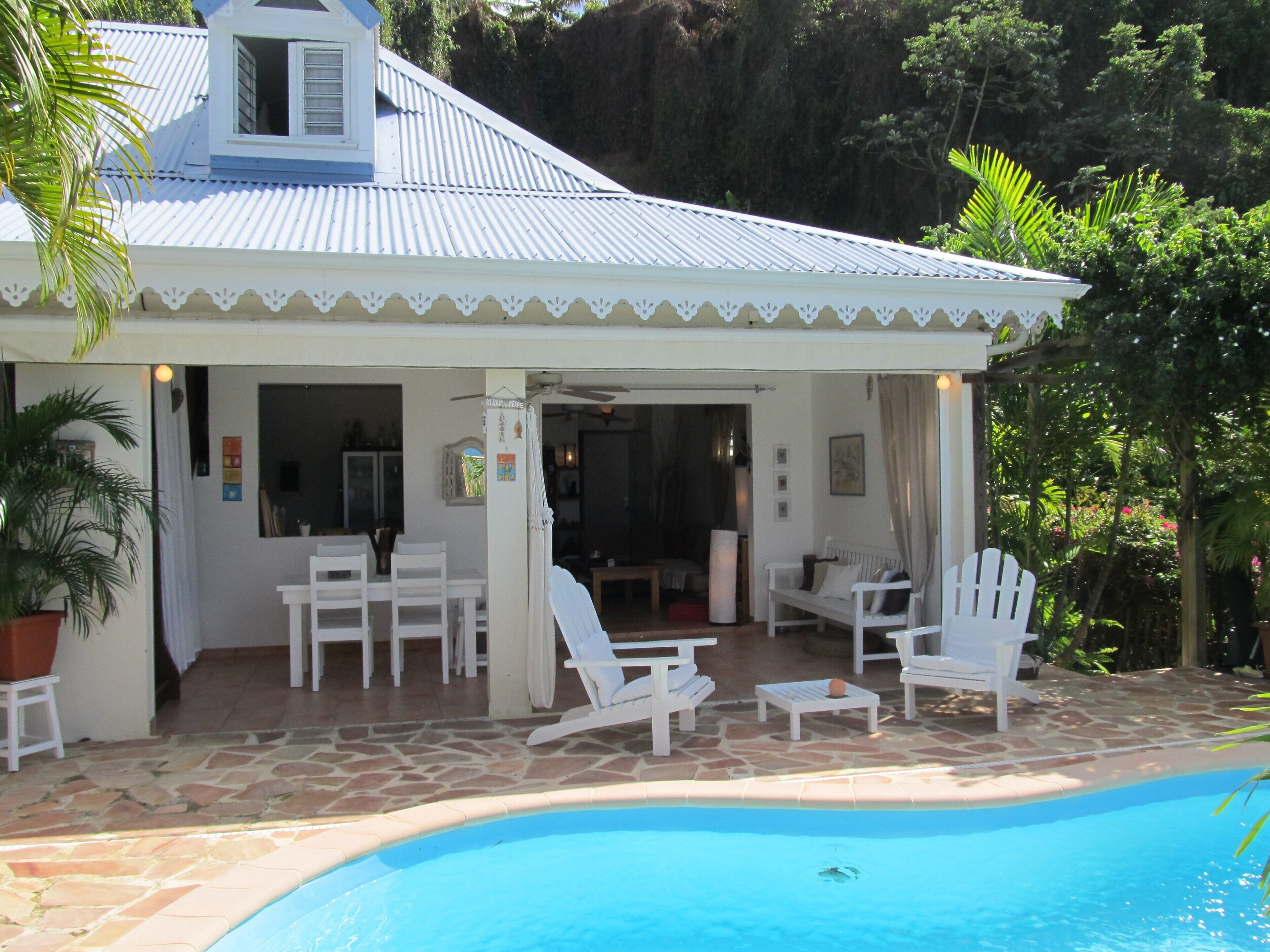 Ein Haus mit Pool, weißer Möbel und einer überdachten Terrasse.
