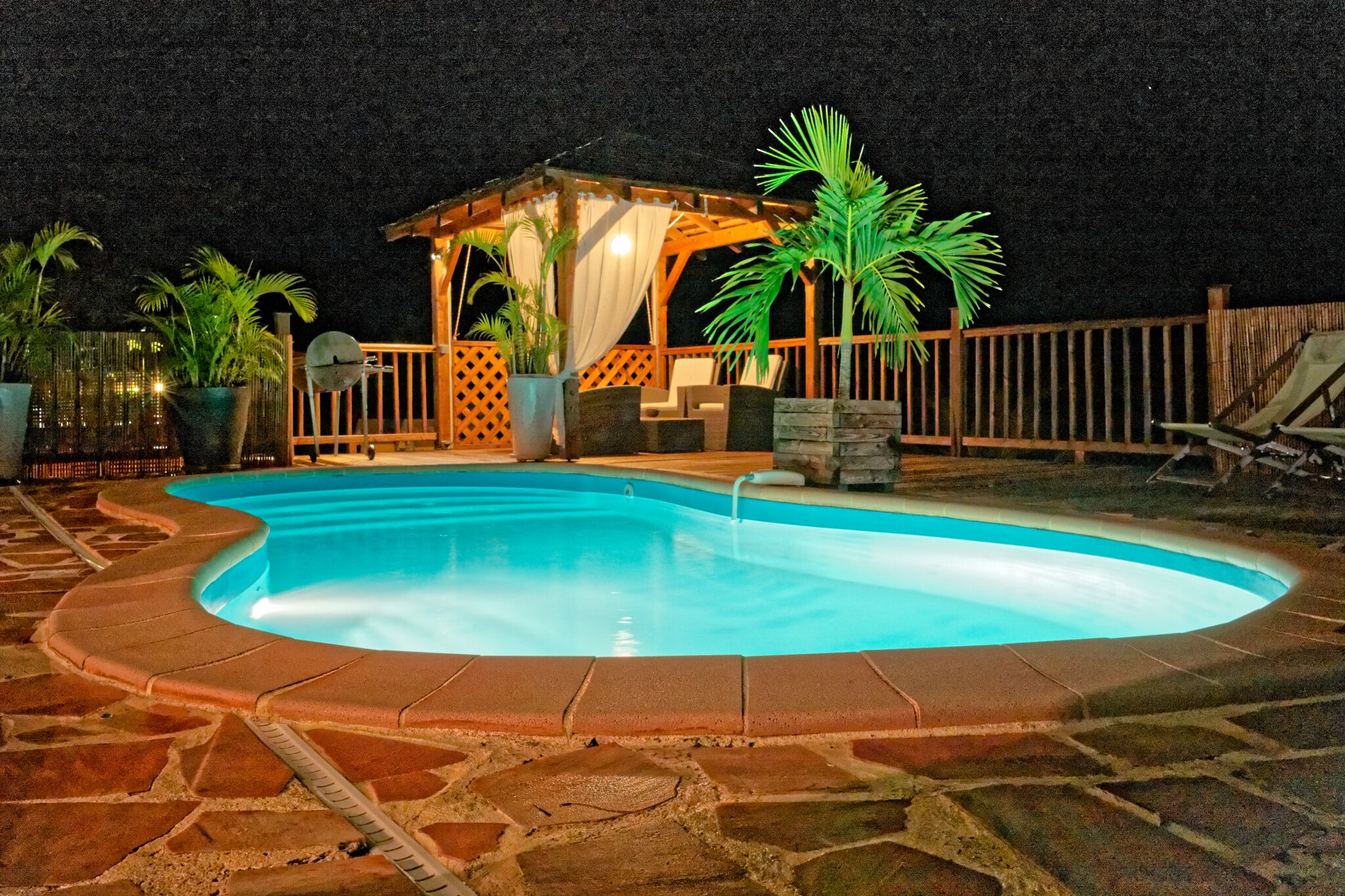 A swimming pool with a wooden deck and a gazebo.