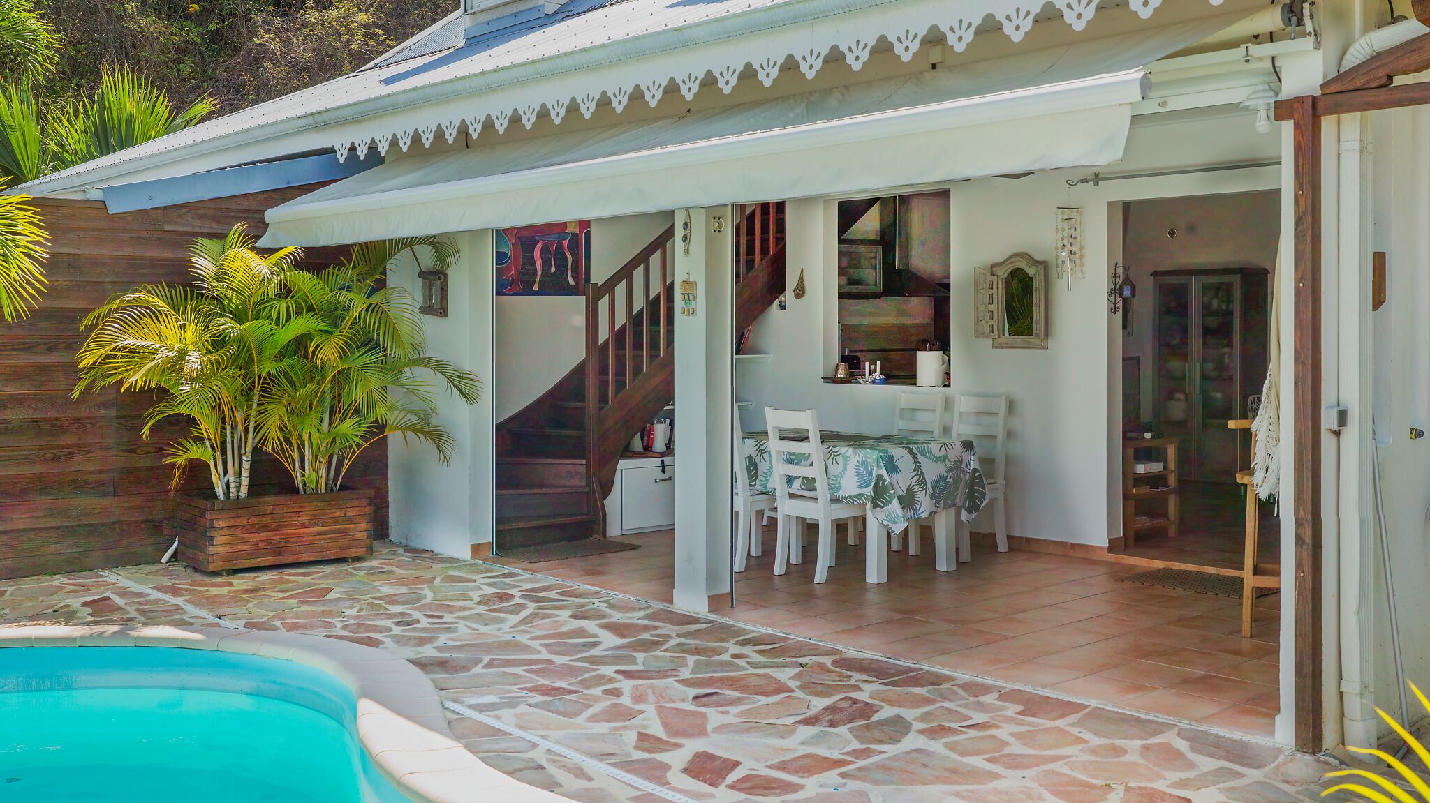 A covered outdoor area with a pool, a dining table, and chairs.